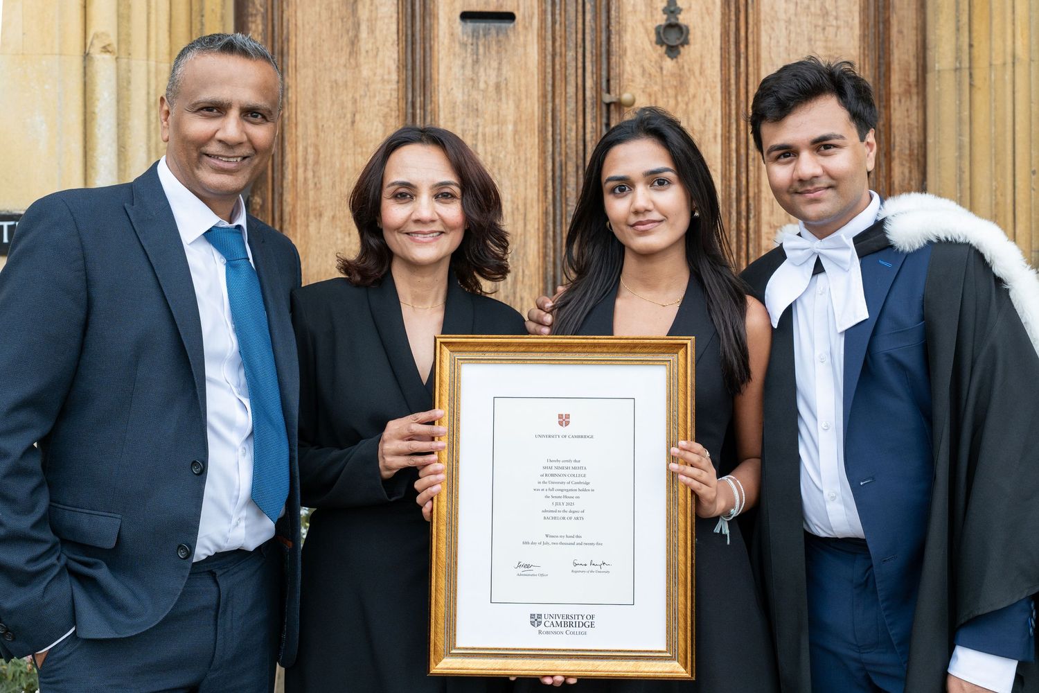 Four people in business attire proudly display a framed certificate or award document outside a building.