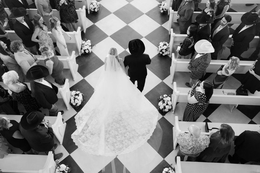 Aerial view of a chess competition showing multiple chess boards and players arranged on a checkered floor pattern in rows.