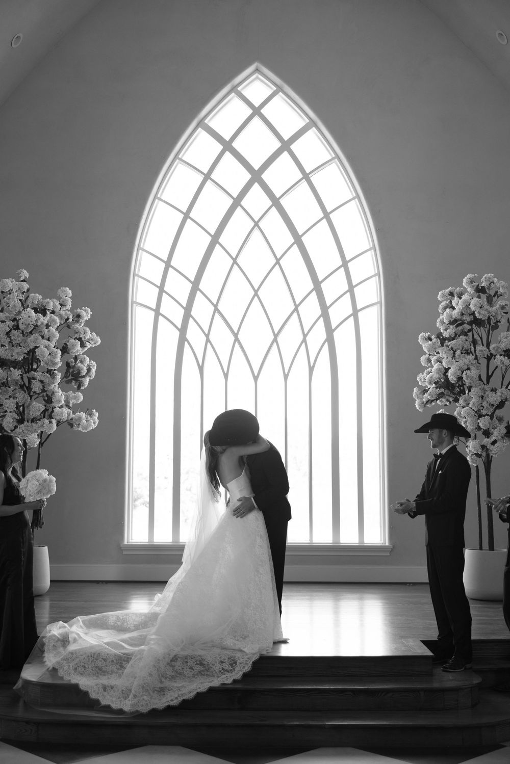A dramatic series of black and white photos showing a wedding dress silhouette in a church with cathedral windows and floral decor.
