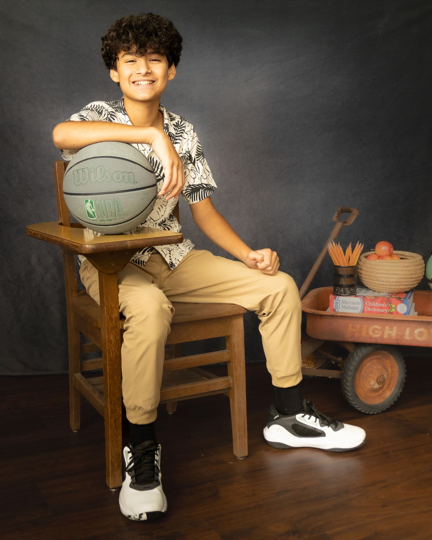 Basketball themed youth portrait with vintage props featuring a kid sitting on wooden chair holding a Spalding ball.