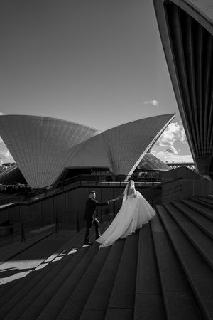Dramatic black and white wedding photo at Sydney Opera House with iconic sail architecture.
