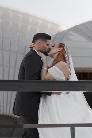 Romantic wedding moment captured against white architectural backdrop of Sydney Opera House.