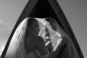 Dramatic black and white wedding portrait framed by Sydney Opera House architecture.