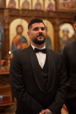 Formal wedding portrait inside a church with religious icons and artwork visible in the background.