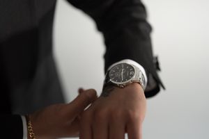 Close-up shot of a silver watch on someone's wrist with formal attire.