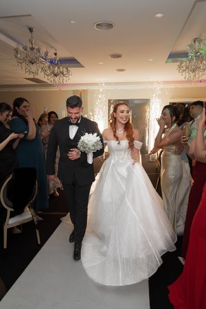 Grand entrance at wedding reception with sparklers and chandeliers lighting the path.