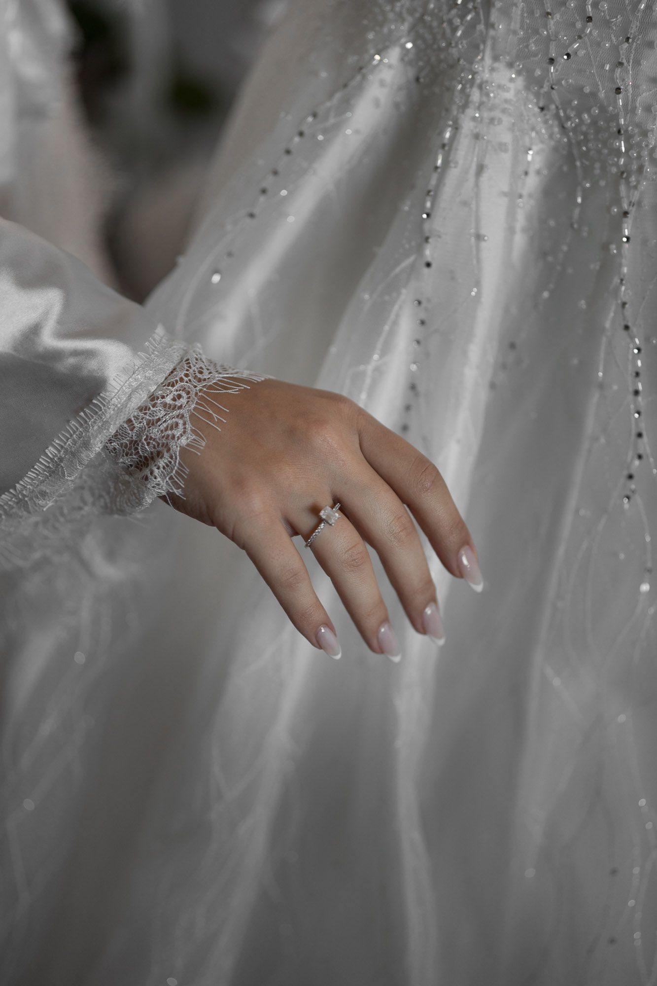 Close-up detail of sparkling beadwork and crystals on a white wedding gown.