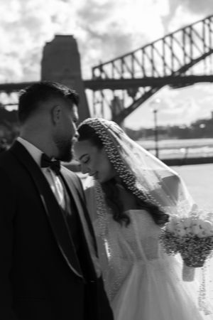 Wedding couple embracing in front of Sydney Harbour Bridge in black and white.