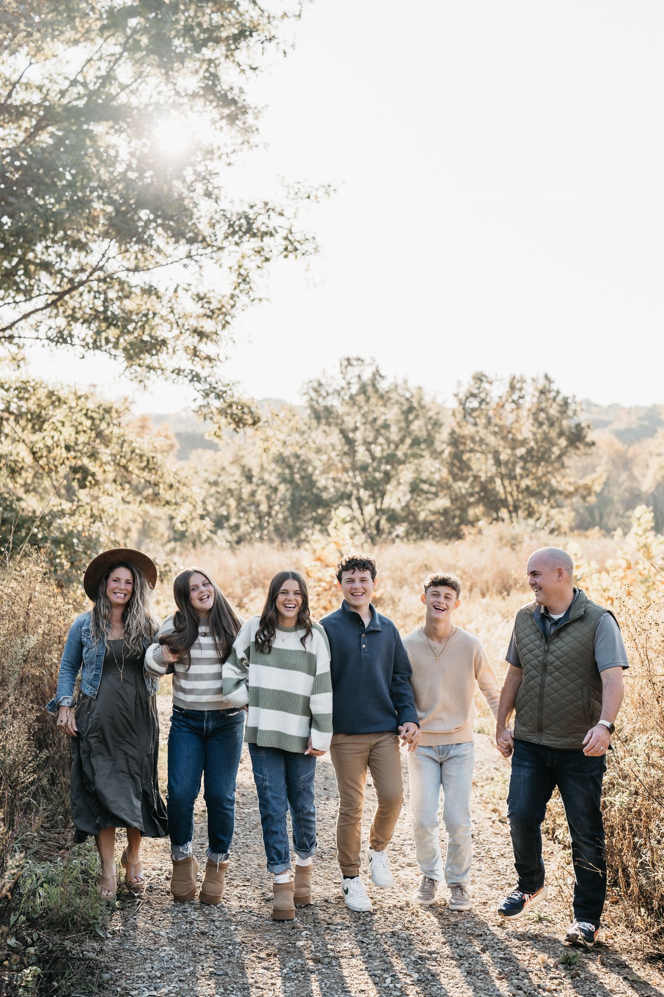 A group of people walking together in casual attire along a sunlit path during golden hour.