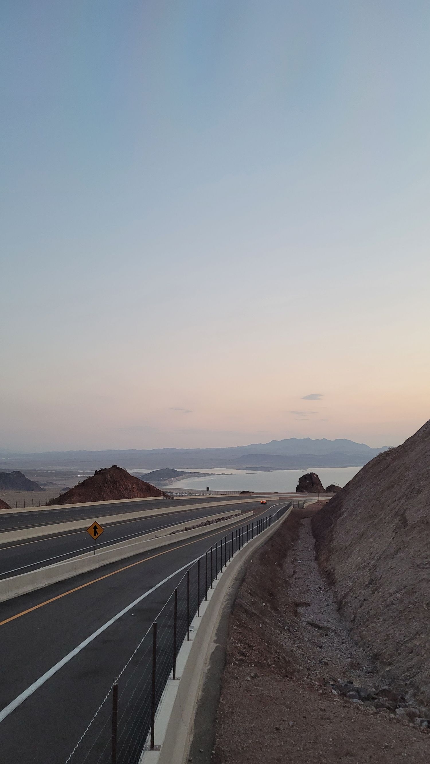 Desert highway at sunset with mountains in the distance near the Nevada–Arizona border.