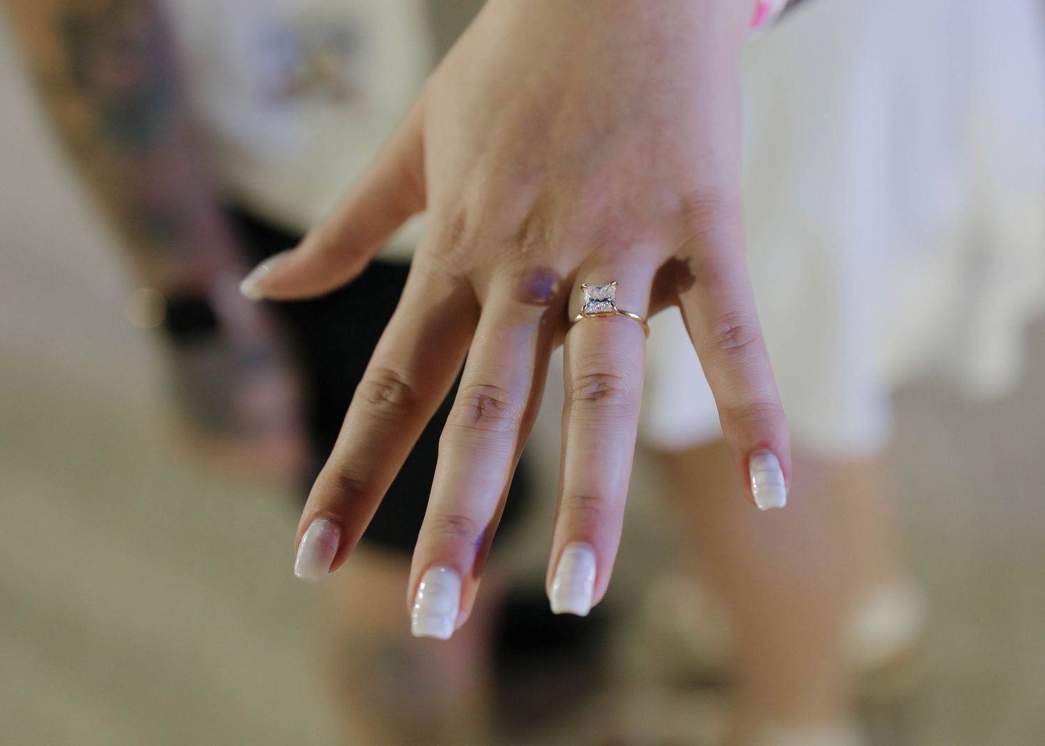 A sequence of photos showing proposal moments on a grassy lawn with trees and a stone building in the background.