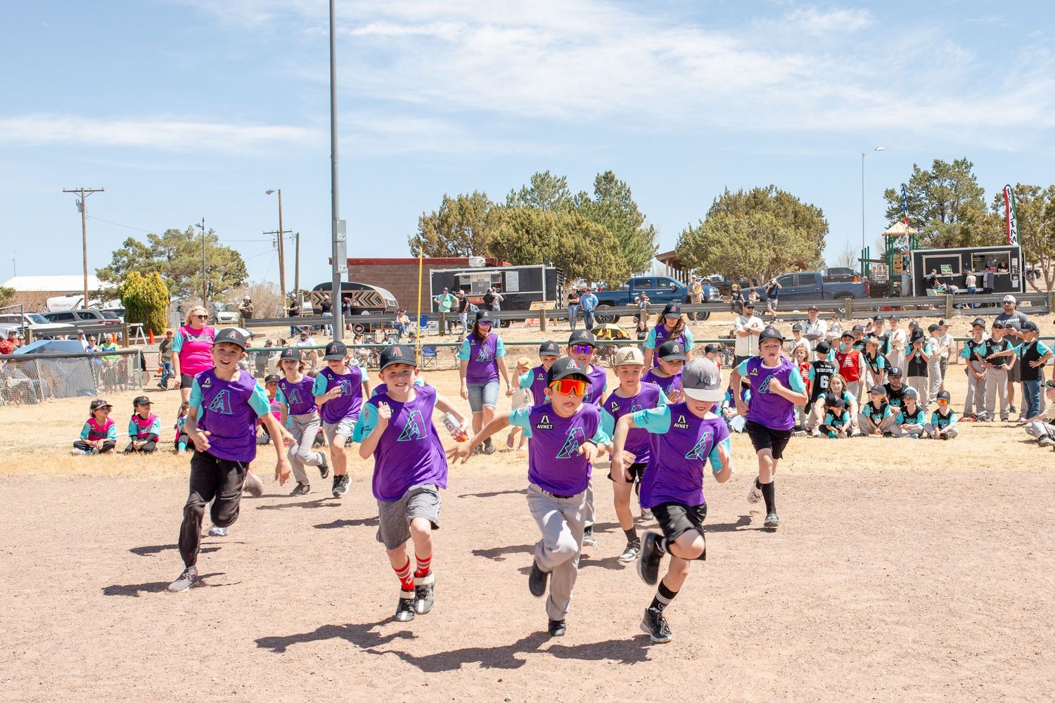 Athletes in purple jerseys running on a sandy beach during a sports event.