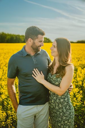 A couple sharing intimate moments in a blooming yellow canola field during sunset.