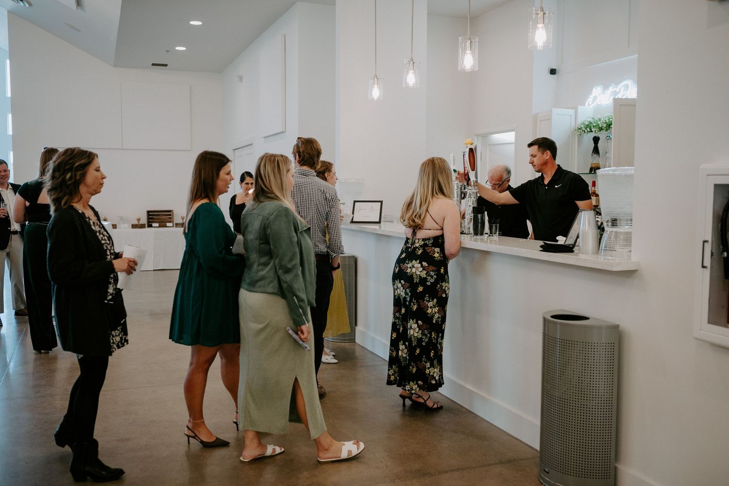 Modern venue lobby with guests waiting in line at a white reception counter.