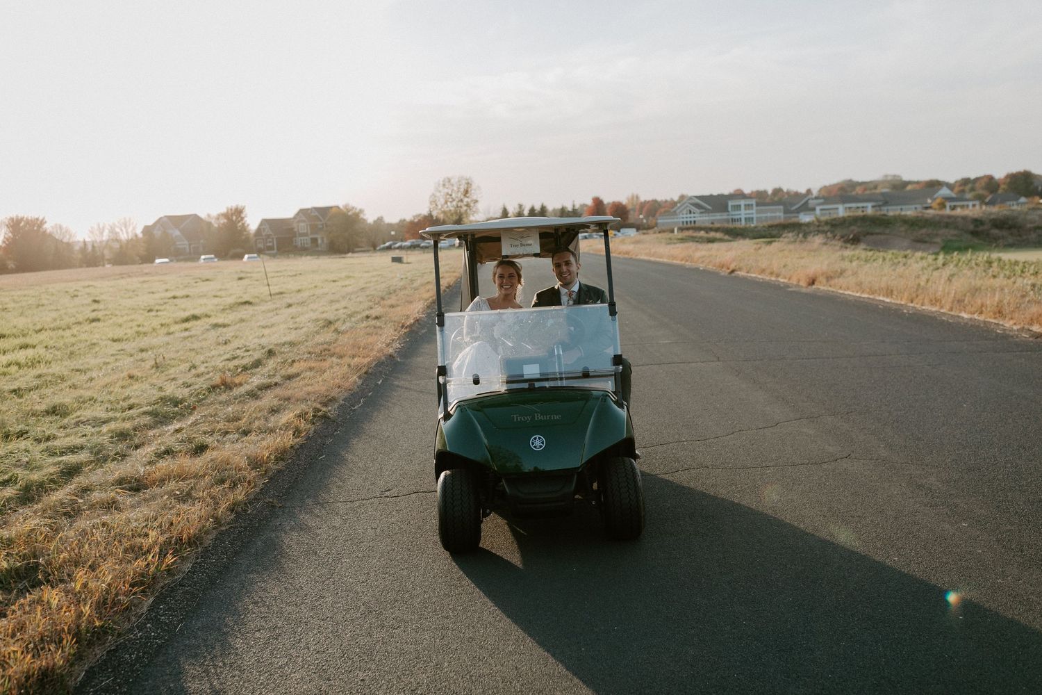 Golf cart parked on path during golden hour at sunset on golf course.