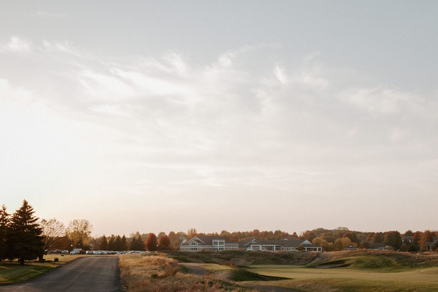 Scenic view of golf course landscape at dusk with winding path.