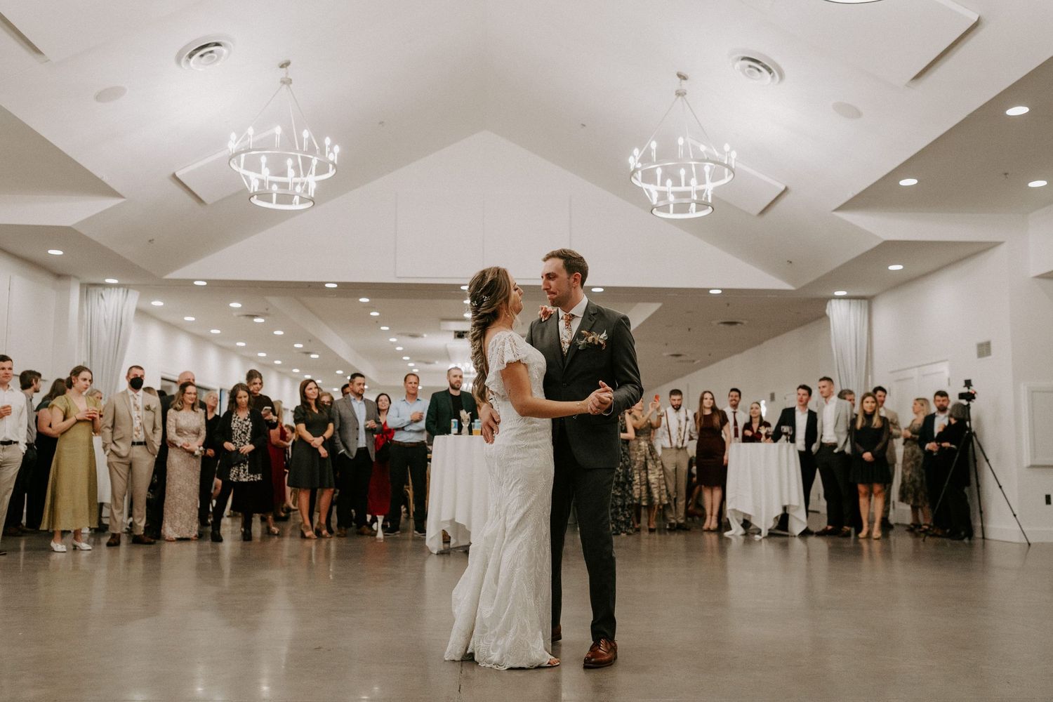 Wedding reception first dance in elegant ballroom with chandeliers.