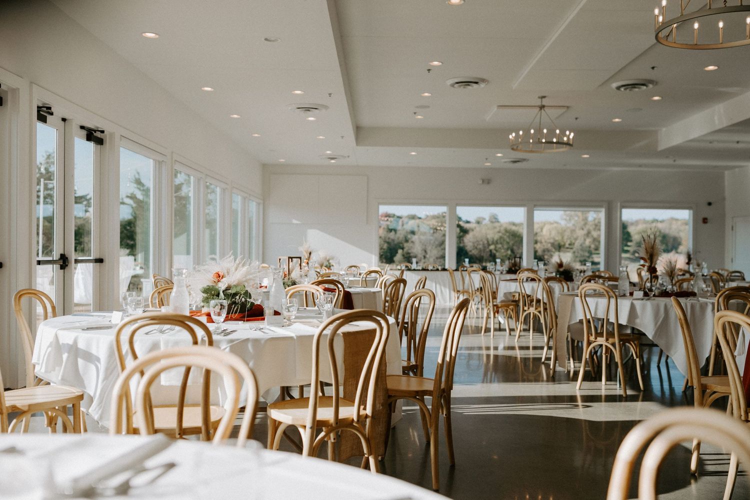 Elegant wedding reception venue with bentwood chairs and large windows letting in natural light.