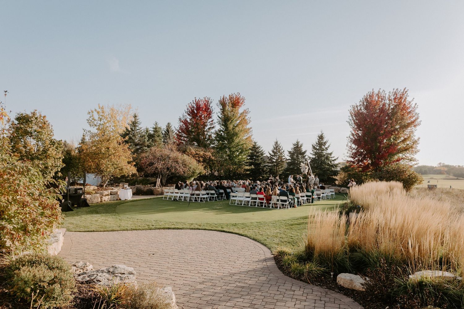 Outdoor wedding ceremony setup in a scenic autumn landscape with evergreen trees.