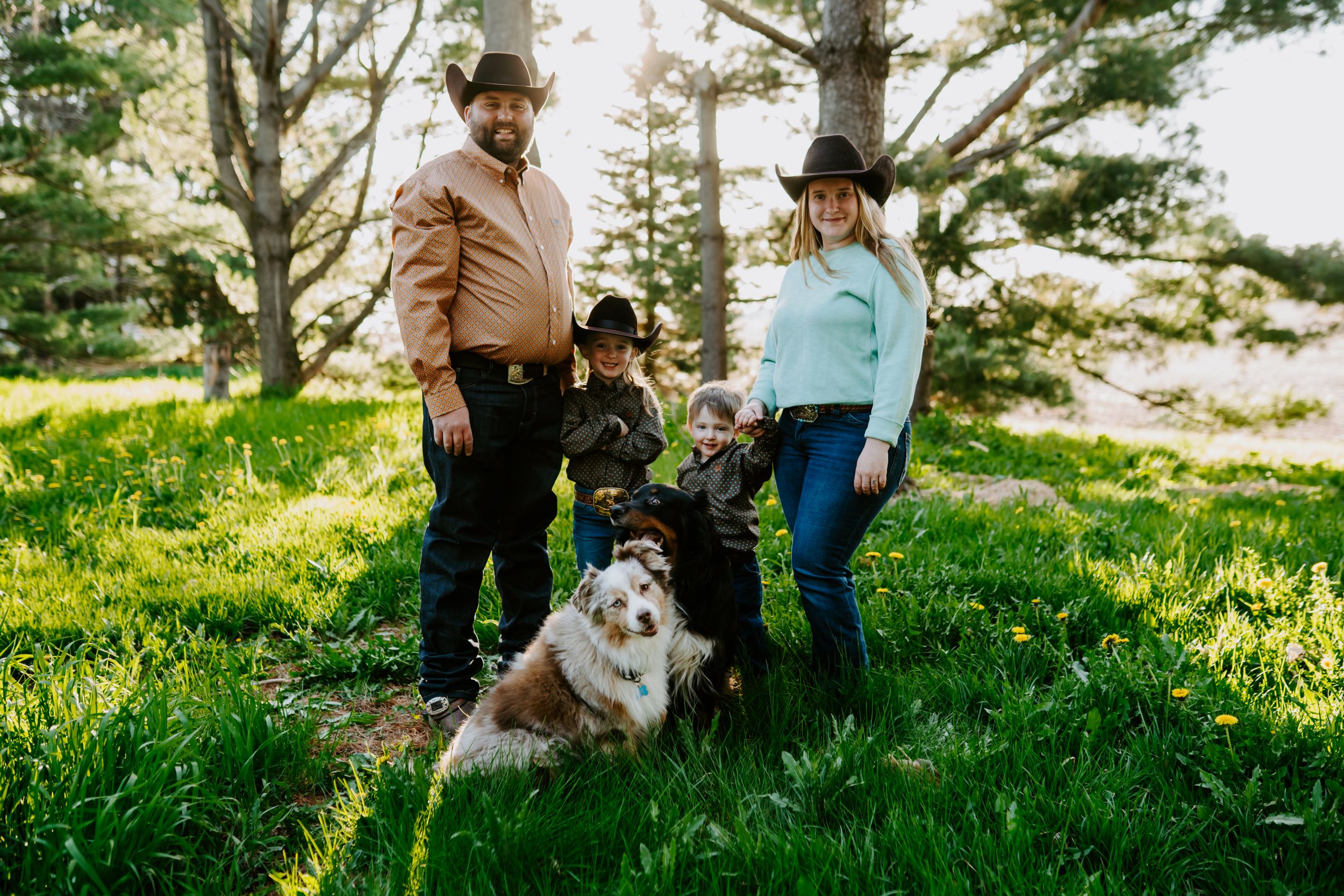 A family and their Australian Shepherd dog pose together in a scenic outdoor setting.