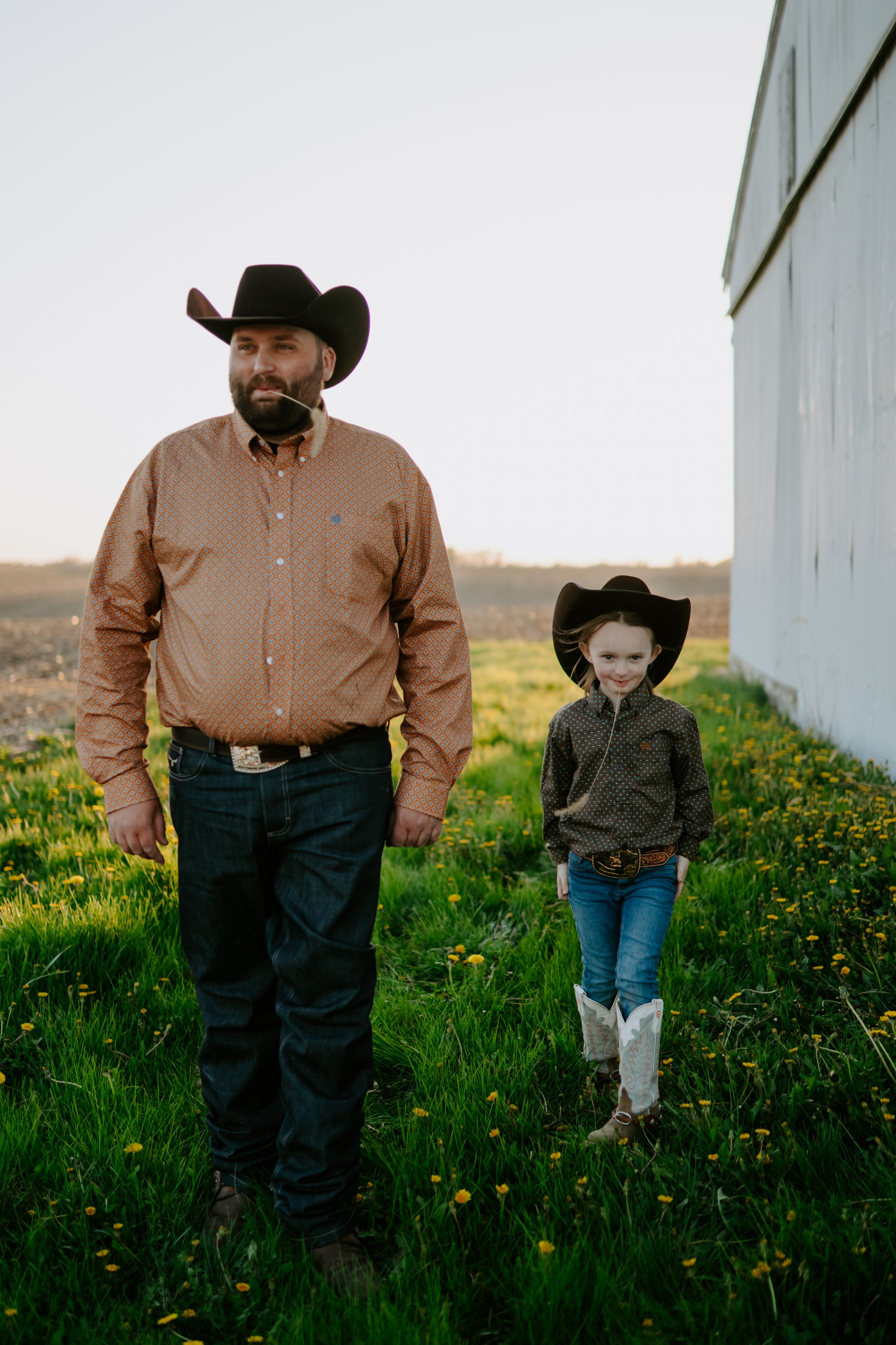 A pair in western attire stroll through a field of spring wildflowers.