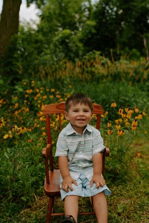 A wooden chair sits in a garden surrounded by vibrant orange and yellow wildflowers.