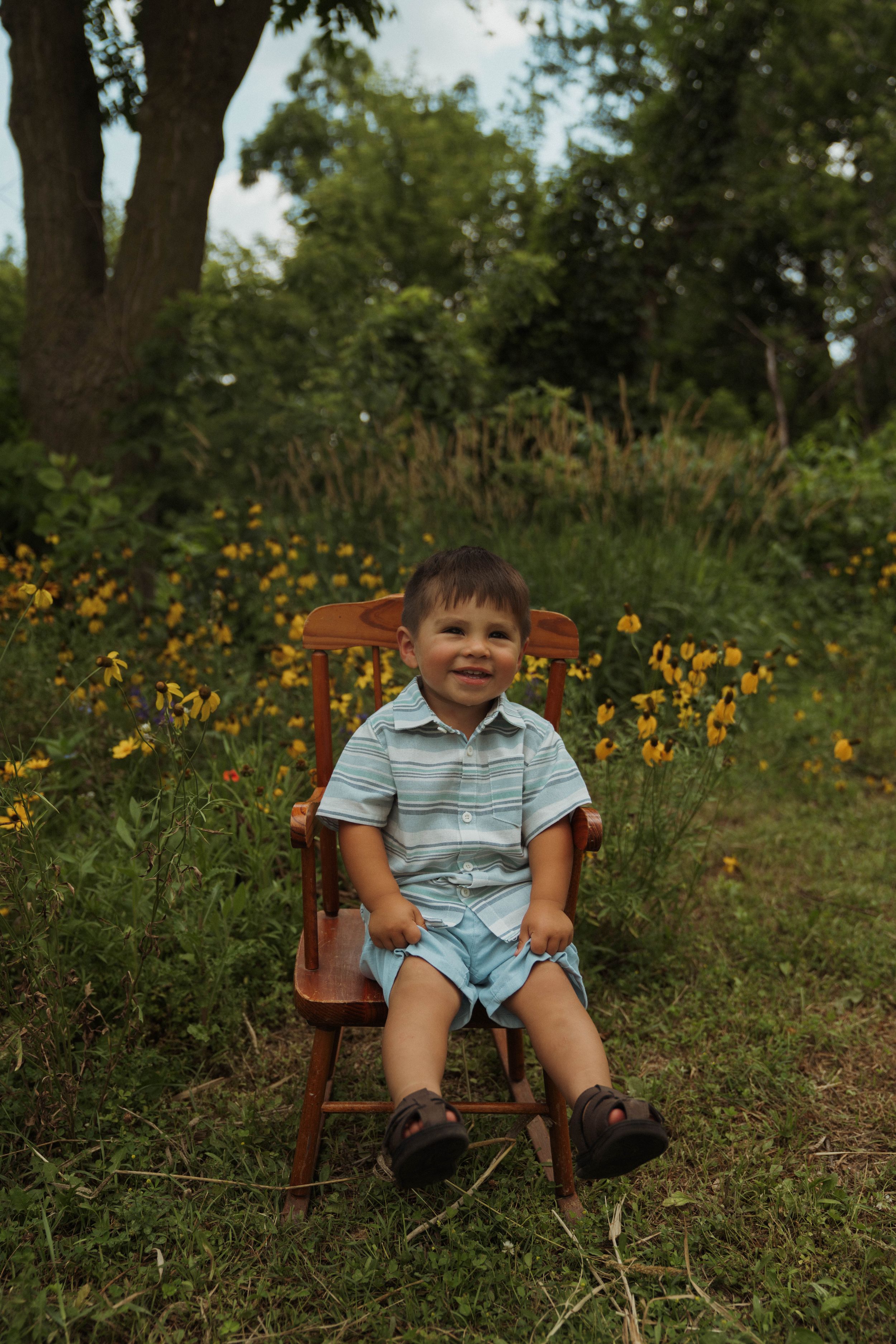 Wooden chair placed among wildflowers in a natural outdoor setting.