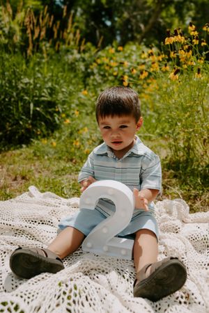 A candid moment captured on a white lace blanket outdoors surrounded by yellow wildflowers.