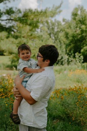 A joyful outdoor family moment in a meadow filled with yellow wildflowers on a sunny day.