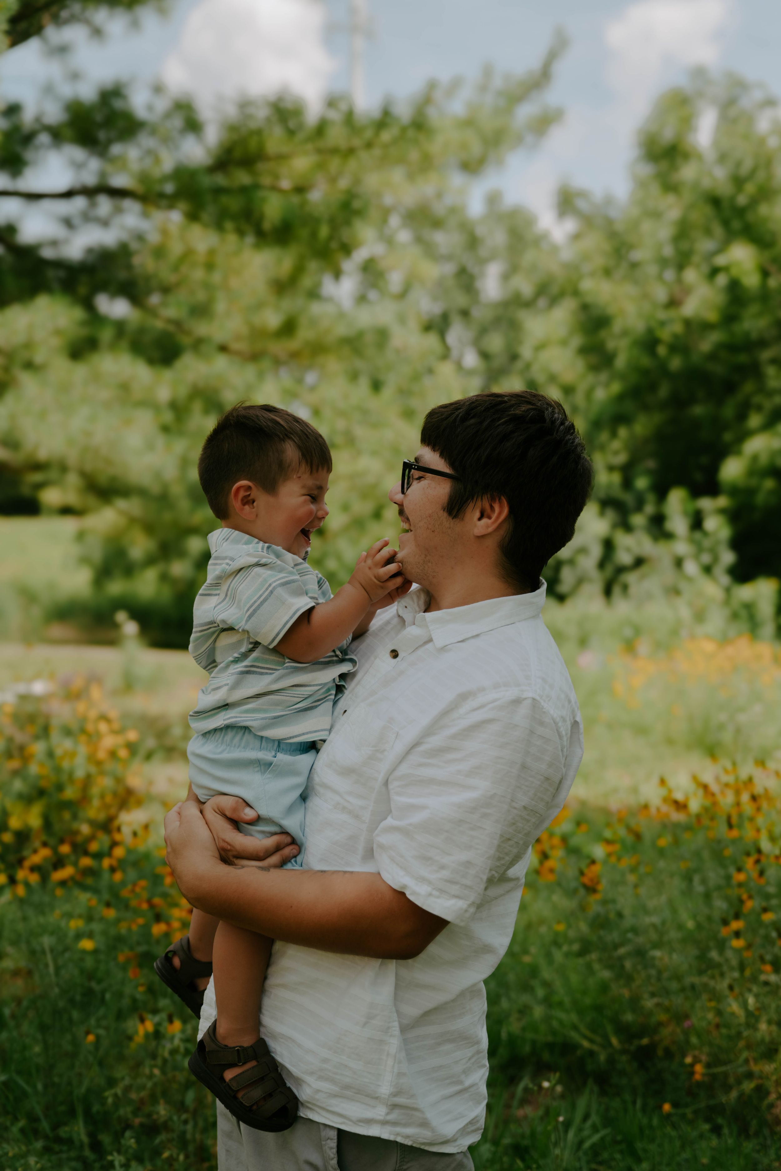 A tender family moment captured in a field of yellow wildflowers.