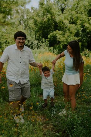 Family playing and having fun together in a field of yellow wildflowers.