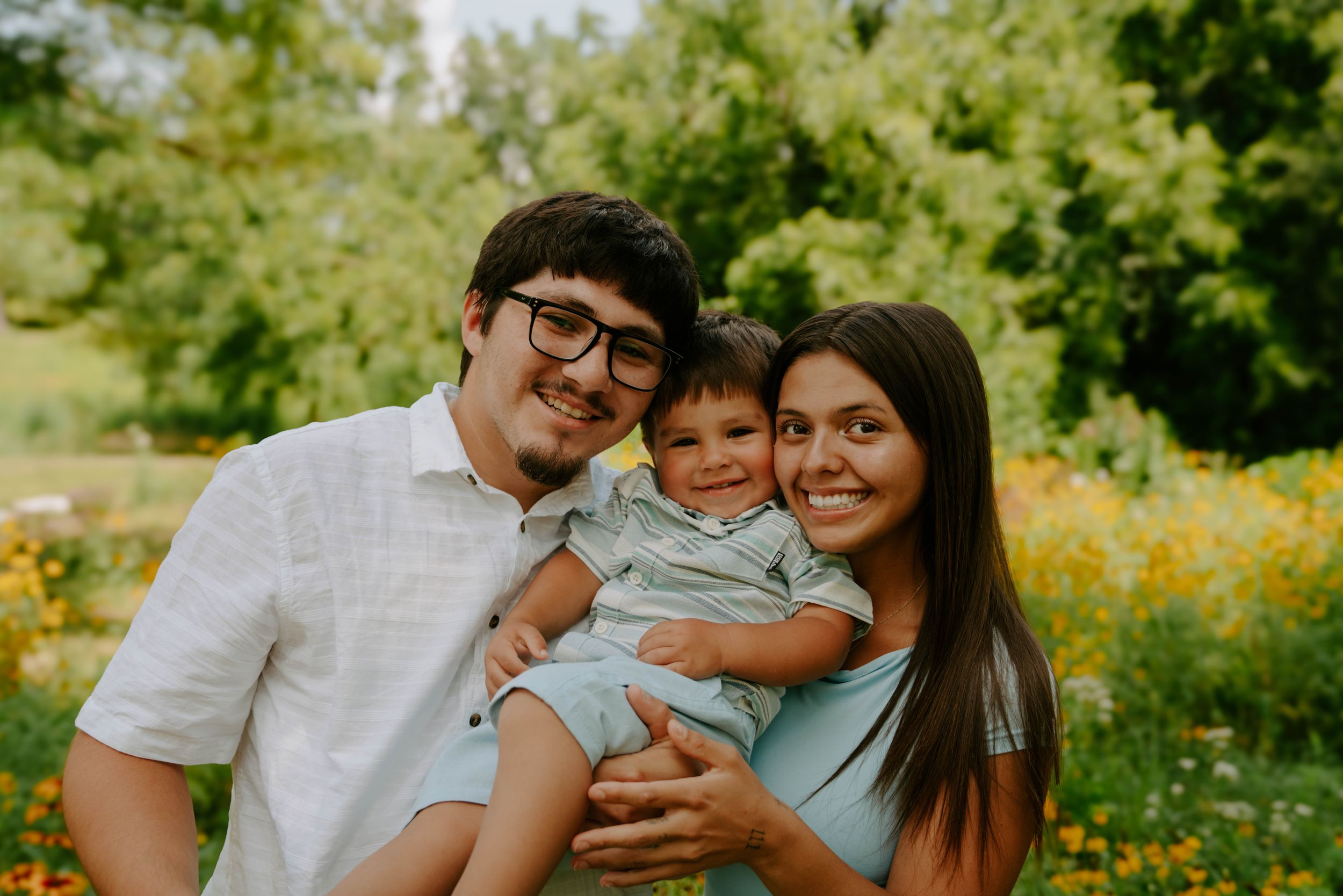 A happy family shares embraces while surrounded by summer flowers.