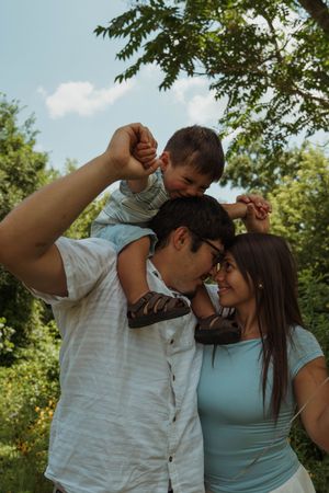 A loving family embracing and laughing together outdoors on a bright summer day.