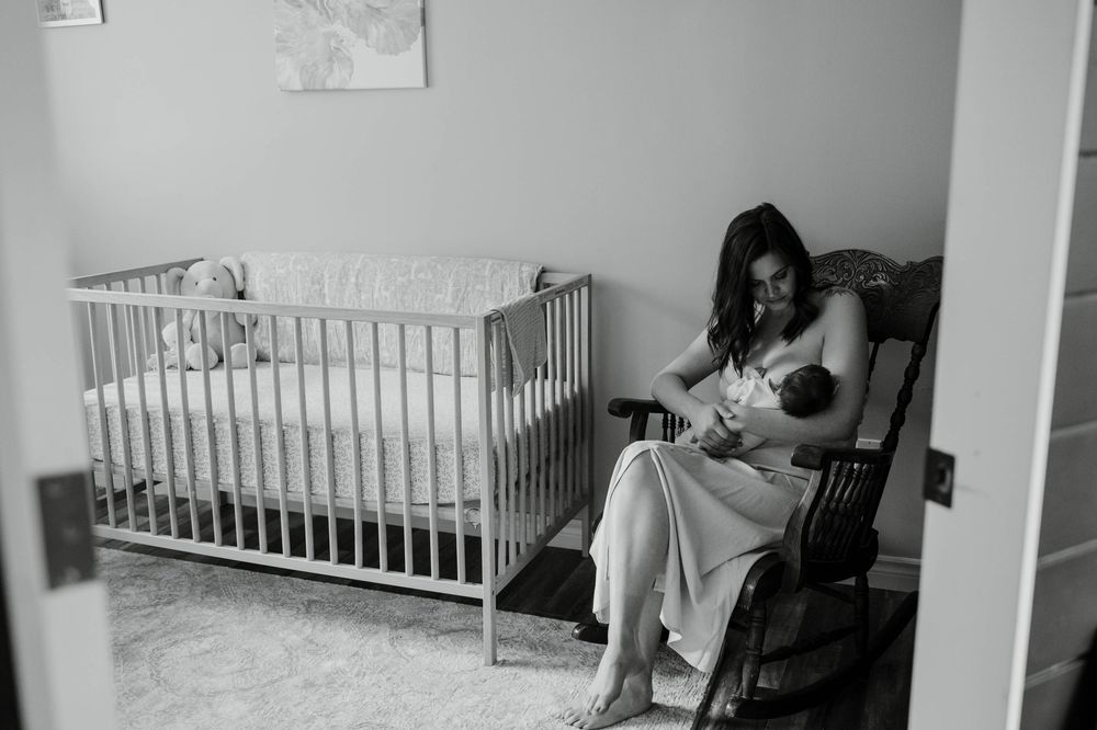 Black and white nursery scene with wooden crib and rocking chair.