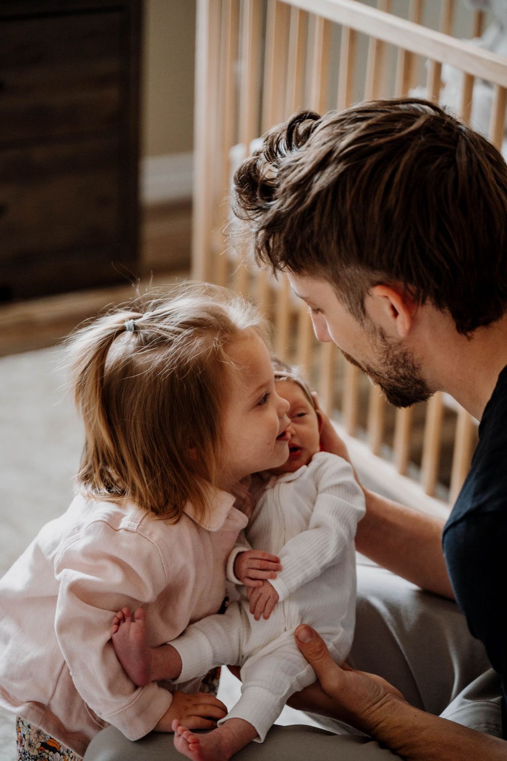 An intimate moment between parent and child shows them sharing laughter in front of a crib.