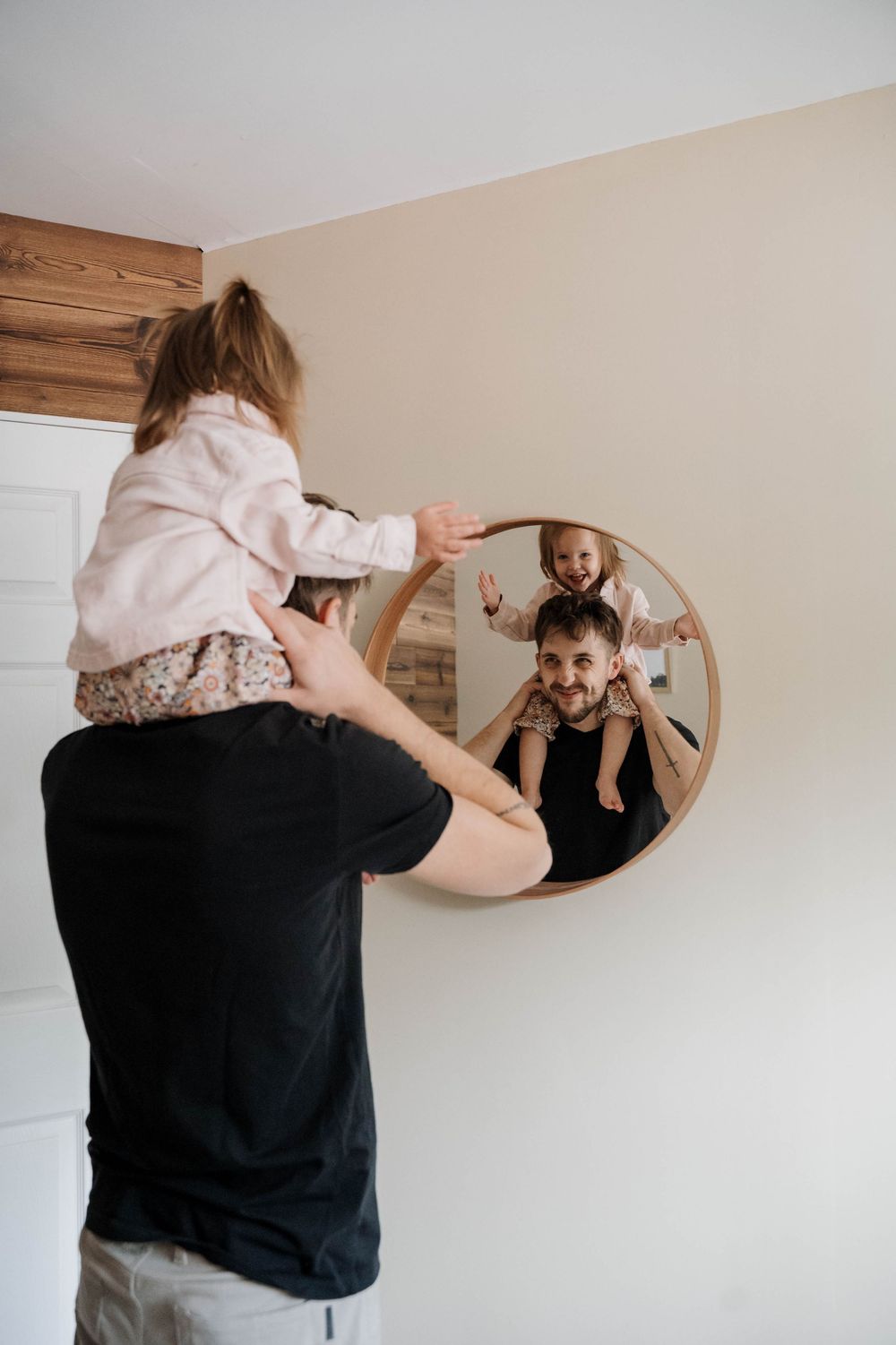 Family bonding moment captured in circular mirror reflection with warm natural lighting.