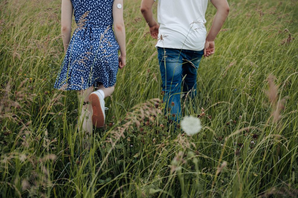 Silhouetted couple stands together in a golden field of grass during magic hour.