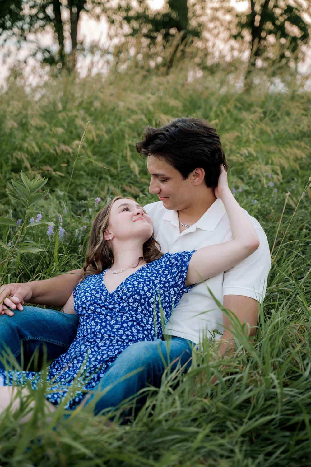 A couple lying together in tall grass during a romantic outdoor photoshoot.