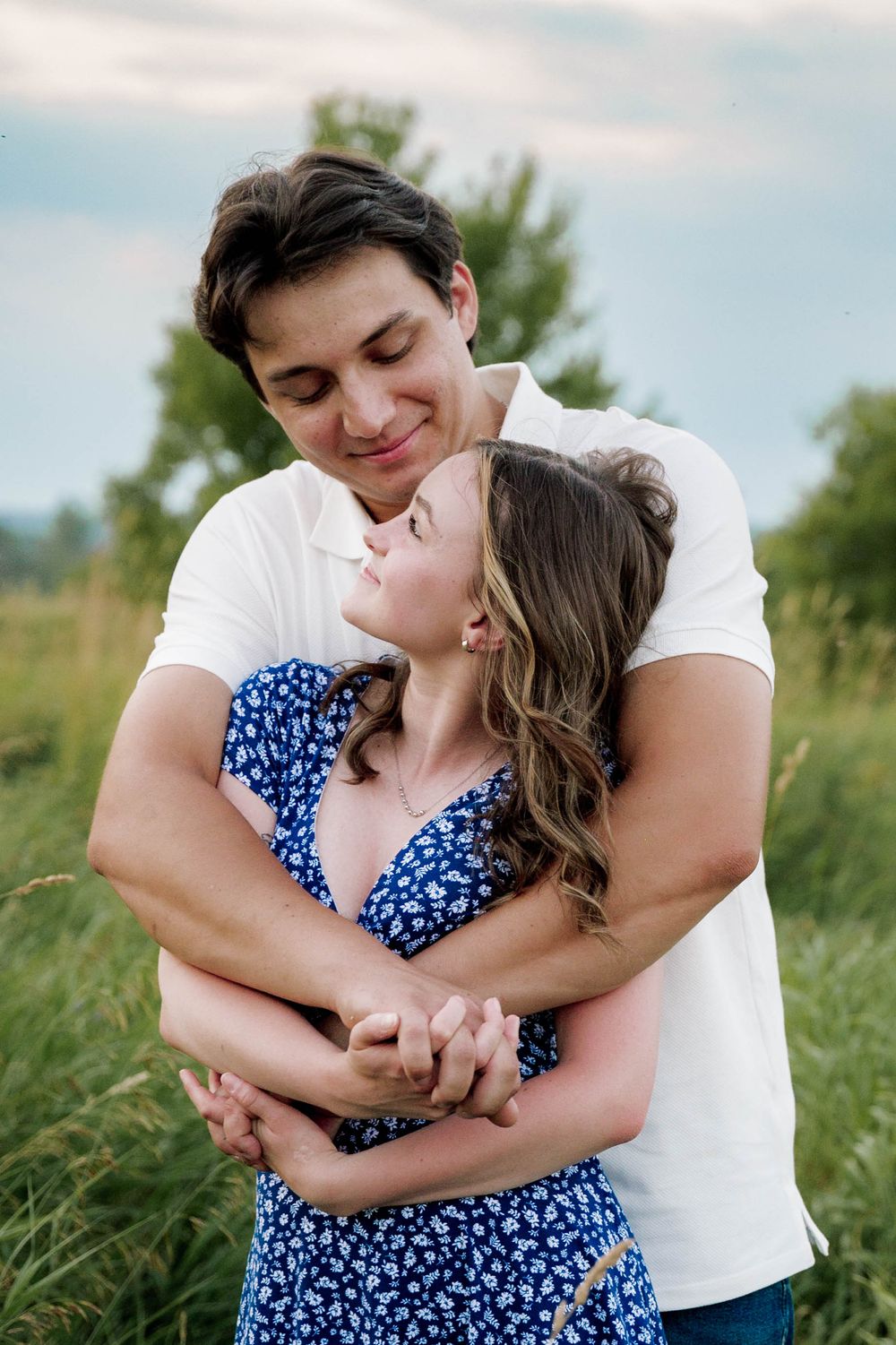 An intimate moment between a couple in a field with natural backlight and soft bokeh.