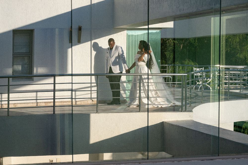 Modern glass walkway connects two buildings with clean architectural lines and reflective surfaces under bright daylight.