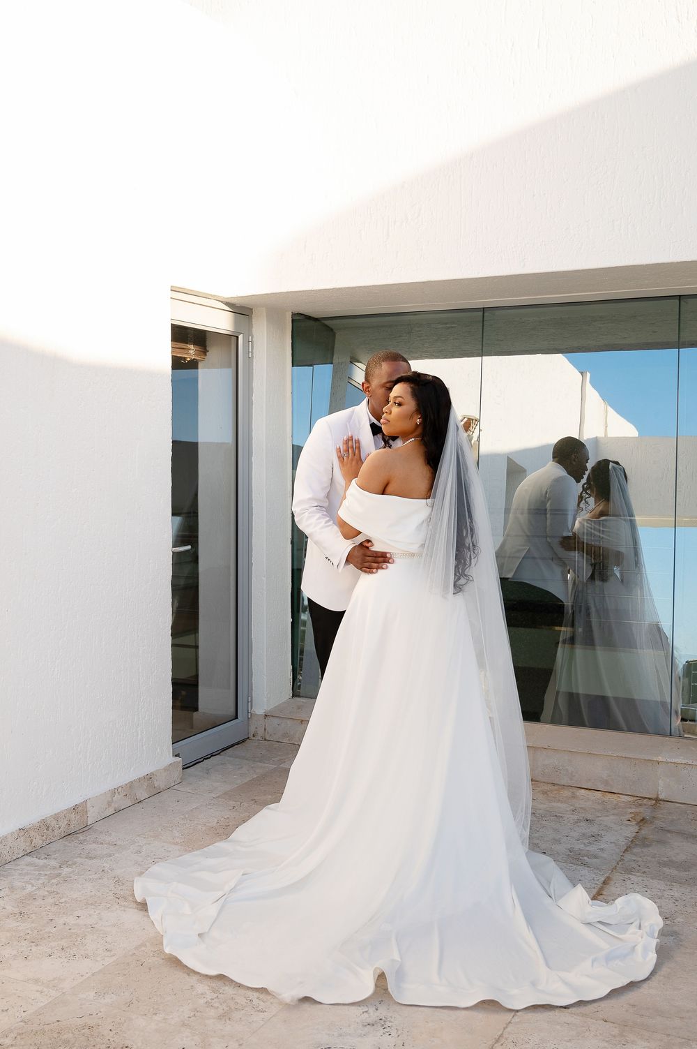 A beautiful wedding couple dances together on a balcony with scenic views, their white dress flowing elegantly.