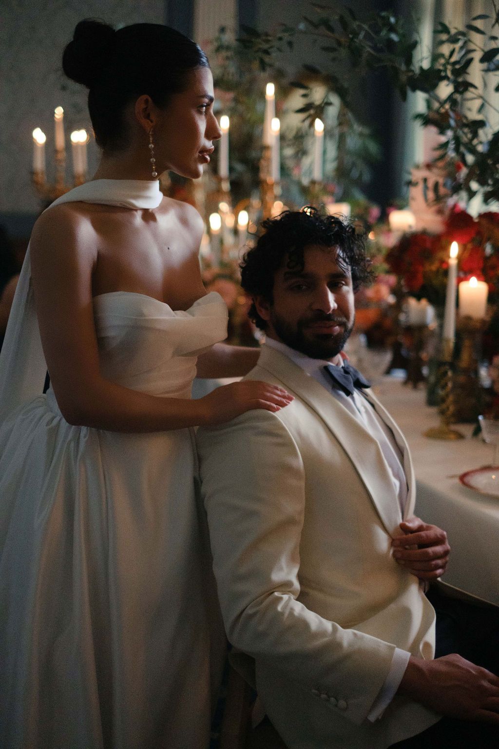 Intimate candlelit wedding reception moment with couple in white attire.