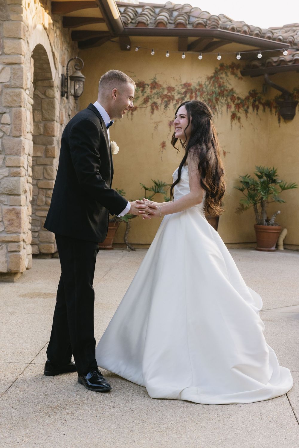 Elegant dance sequence shows couple at outdoor villa celebration in formal wedding attire with stone columns in background.