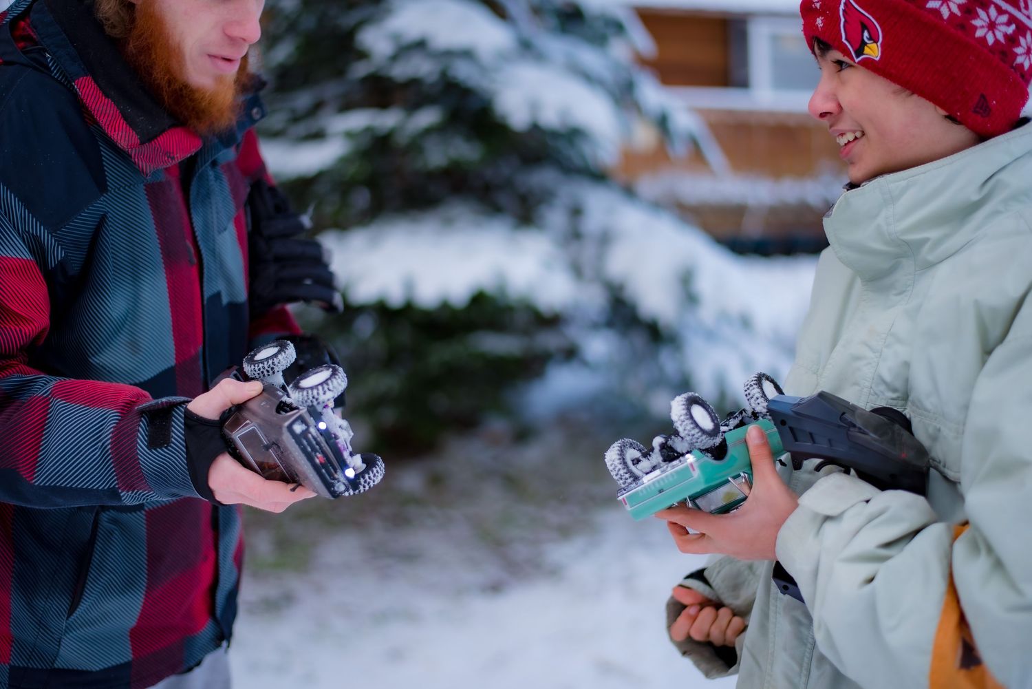 Two people in winter clothes playing with toy cars in the snow. on whidbey island.
