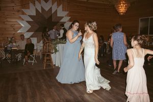 Wedding party dancing in a rustic barn venue with wooden walls and string lights.