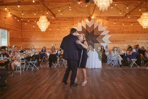 Wedding reception in a timber-lined venue decorated with chandeliers and string lights.