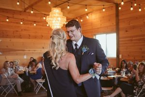 Elegant wedding reception in a wood-paneled venue with string lights and crystal chandeliers.