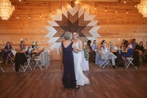 Dancing during a wedding reception in a rustic venue with wooden walls and chandeliers.