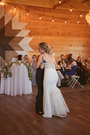 Wedding reception in rustic barn venue with white-clothed tables and dance floor.
