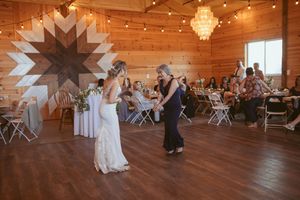 Wedding dance in a rustic barn venue with wooden walls and chandelier lighting.